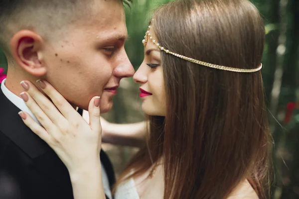 Beautiful young wedding couple is kissing and smiling in the park — Stock Photo, Image