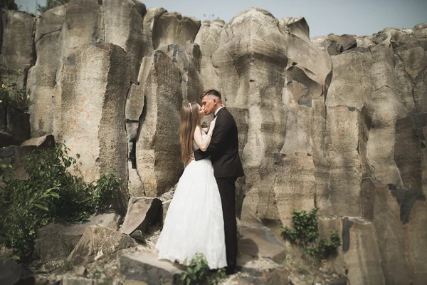 Nádherná nevěsta, ženich, líbání a objímání poblíž útesů s nádherným výhledem — Stock fotografie