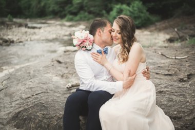 Zarif nazik şık damat ve gelin taşlarla Nehri yakınında. Evlilik çift aşık