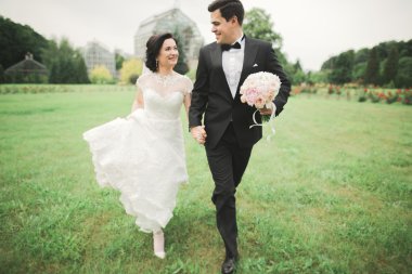 Yeni evli çift el ele tutuşurken parkta koşup zıplıyorlar.