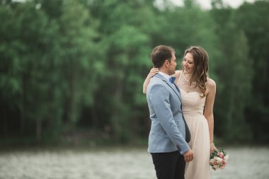 Zarif güzel düğün çifti bir göl kenarında günbatımında poz