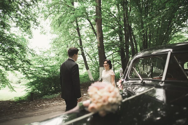 Vackra nygifta par poserar nära retro svart bil — Stockfoto