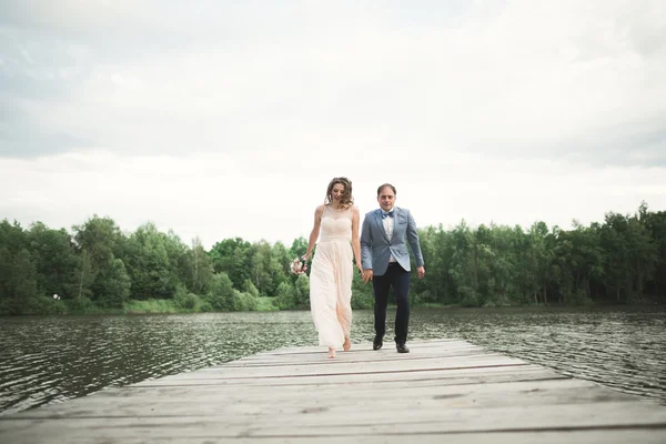 Hochzeitspaar, Braut, Bräutigam spazieren und posieren auf Seebrücke — Stockfoto