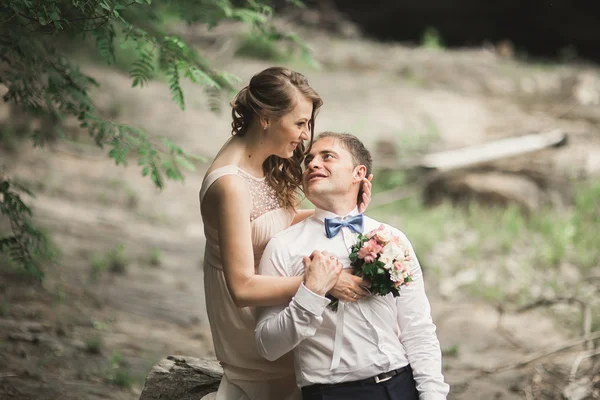 Elegant mjuka eleganta brudgummen och bruden nära floden med stenar. Bröllop par i kärlek — Stockfoto