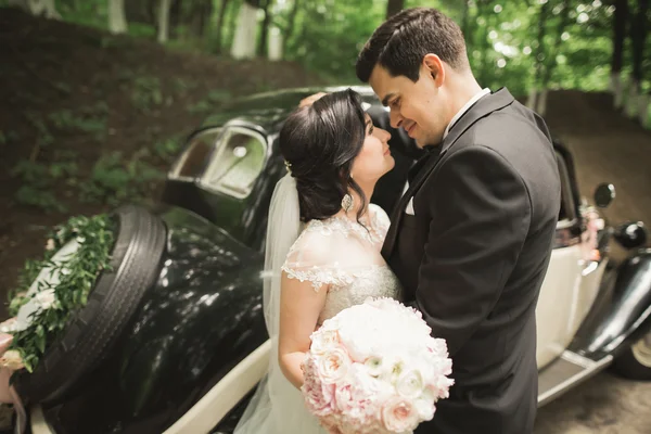 レトロな黒車の近くにポーズ美しい新婚カップル — ストック写真