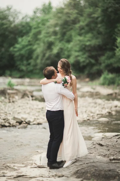 Elegantní jemný stylový ženich a nevěsta v blízkosti řeky s kameny. Svatební pár v lásce — Stock fotografie