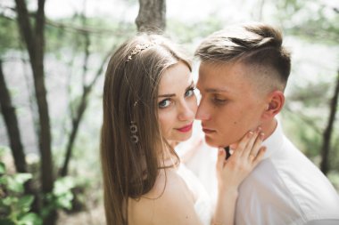 Düğün iki adam, öpüşme ve nehir, dağlar bir arka plan üzerinde sarılma gelin. Güzellik Portresi