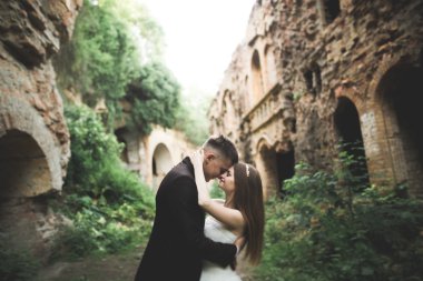 Güzel, romantik bir düğün. Yeni evliler. Eski kalenin yakınlarında sarılıyorlar.