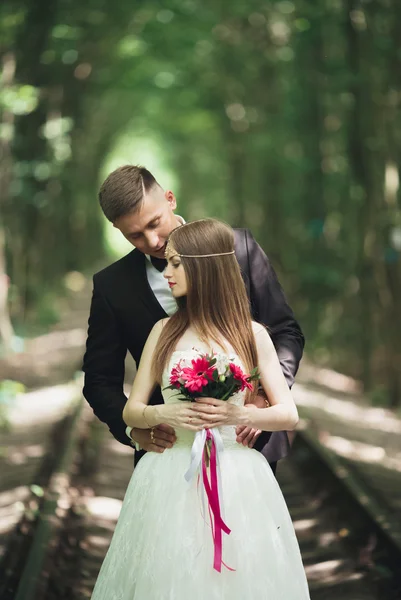 Casal de casamento jovem, noiva e noivo posando em uma trilha ferroviária — Fotografia de Stock