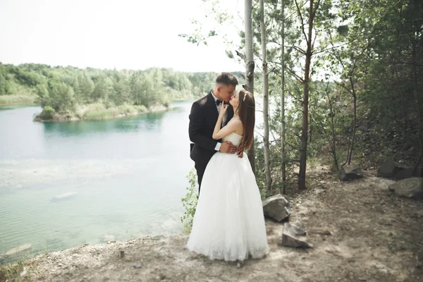 Boda pareja enamorada besándose y abrazándose cerca de rocas en hermoso paisaje — Foto de Stock