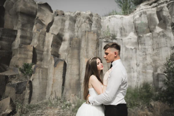 Svatební pár v lásce líbání a objímání v blízkosti skal na krásné krajině — Stock fotografie