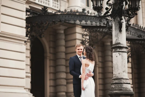 Hermosa pareja de boda, novia, novio besándose y abrazándose contra el fondo del teatro — Foto de Stock