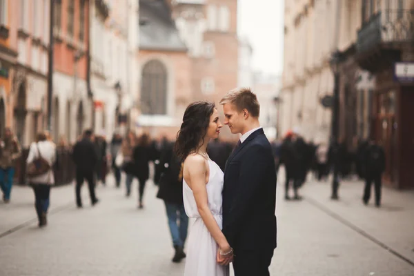 Hermosa pareja de boda, novia, novio besándose y abrazándose de pie en la multitud —  Fotos de Stock