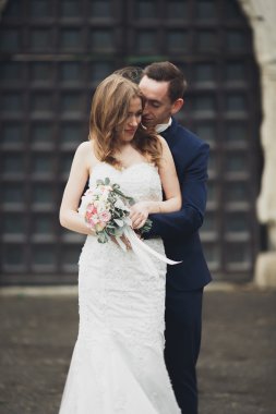 Güzel, romantik bir düğün. Yeni evliler. Eski kalenin yakınlarında sarılıyorlar.