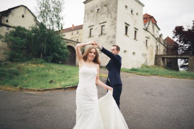 Güzel, romantik bir düğün. Yeni evliler. Eski kalenin yakınlarında sarılıyorlar.