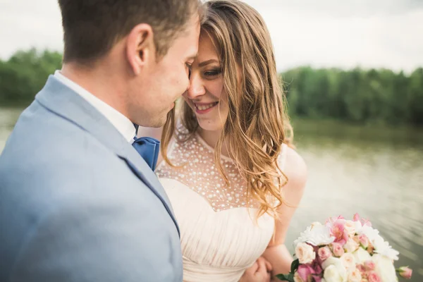 Feliz boda pareja abrazándose y sonriendo el uno al otro en el lago de fondo, bosque —  Fotos de Stock