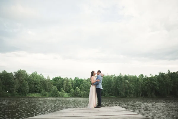 Hochzeitspaar, Braut, Bräutigam spazieren und posieren auf Seebrücke — Stockfoto