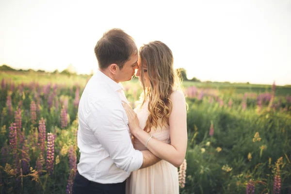 Casal de casamento jovem andando no campo com flores — Fotografia de Stock