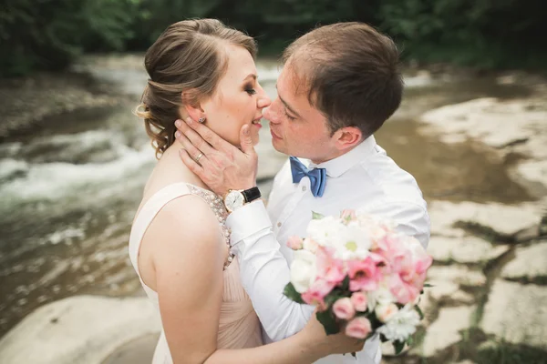 Bruden ler med slutna ögon medan brudgummen vidrör hennes ansikte fint — Stockfoto
