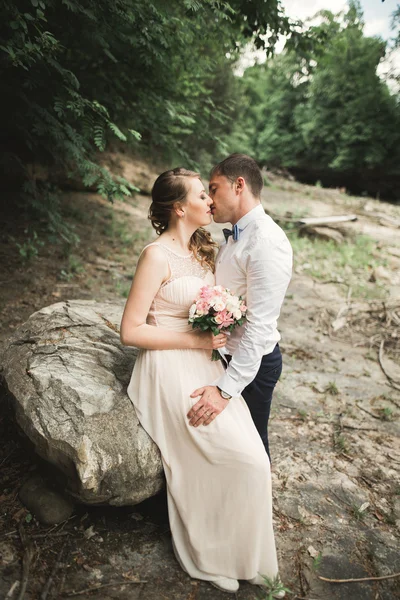 Elegante sanfte stilvolle Bräutigam und Braut in Flussnähe mit Steinen. Hochzeitspaar verliebt — Stockfoto