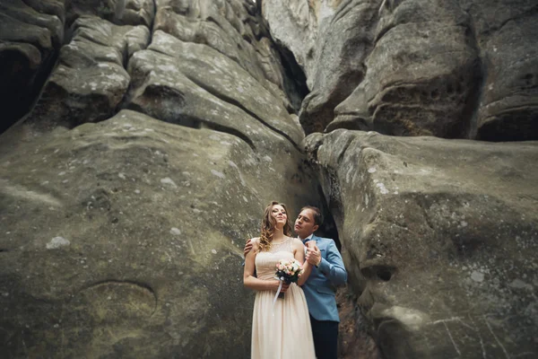 Couple de mariage heureux embrasser et étreindre près d'une haute falaise — Photo