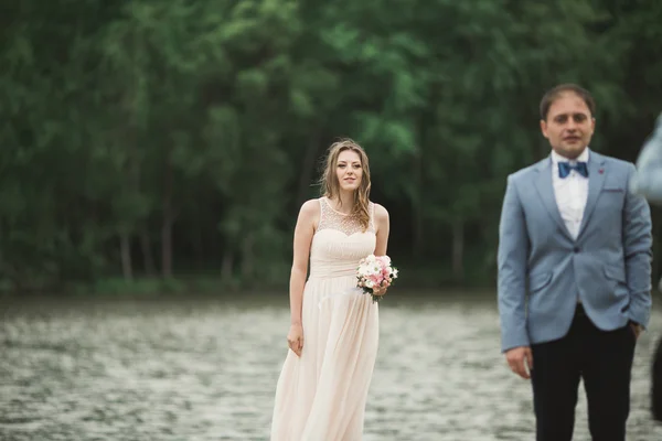 Elegante schöne Hochzeitspaar posiert in der Nähe eines Sees bei Sonnenuntergang — Stockfoto