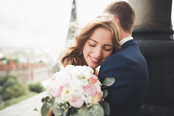 Güzel bir düğün çifti eski kasabanın arka plan panoramik manzarasında öpüşüp sarılıyor. — Stok fotoğraf