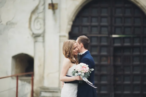 Feliz casamento casal abraçando e sorrindo uns aos outros no fundo velho castelo — Fotografia de Stock