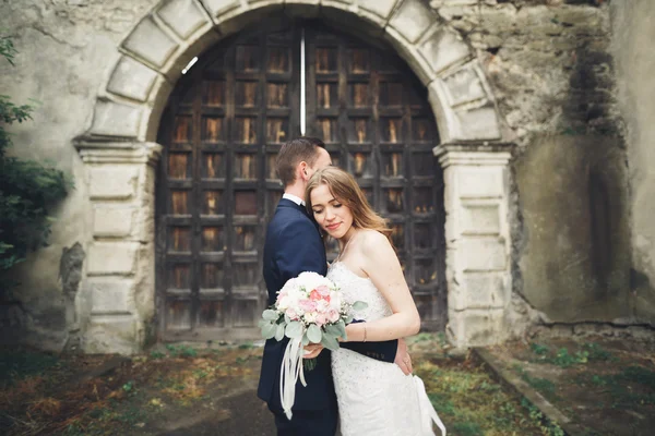 Mutlu düğün kaç sarılma ve birbirlerine arka plan eski kale üzerinde gülümseyen — Stok fotoğraf