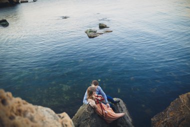 Mavi Denizi çevresinde büyük bir taş üzerinde oturan Düğün çifti