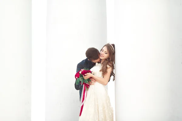 Casal bonito, noiva e noivo posando perto de grande coluna branca — Fotografia de Stock