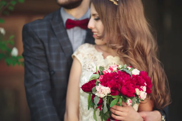 Wedding couple hugging, the bride holding a bouquet of flowers in her hand, groom embracing — Stock Photo, Image