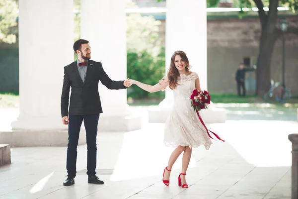 Casal bonito, noiva e noivo posando perto de grande coluna branca — Fotografia de Stock