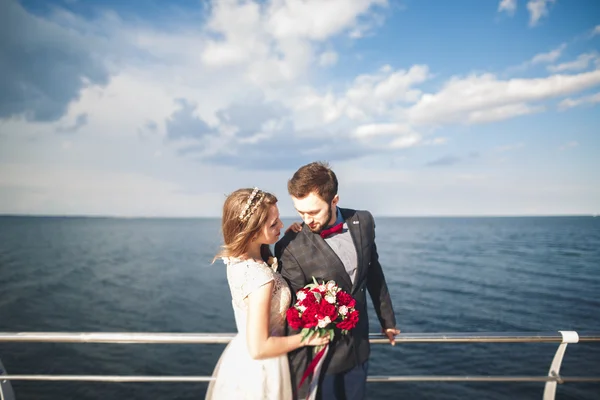 Séta a tengerparton naplementekor, nászutas esküvői pár. — Stock Fotó