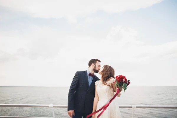 Casamento casal em pé em um cais sobre o mar — Fotografia de Stock