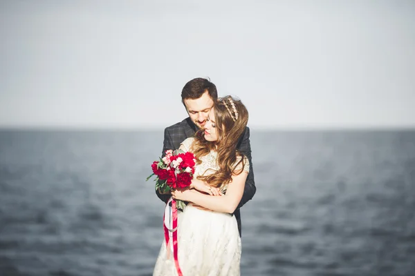 Casamento casal em pé em um cais sobre o mar — Fotografia de Stock