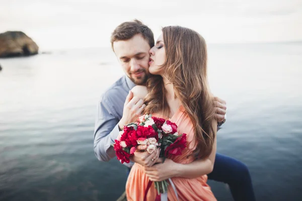 Hochzeitspaar küsst und umarmt sich auf Felsen nahe blauem Meer — Stockfoto