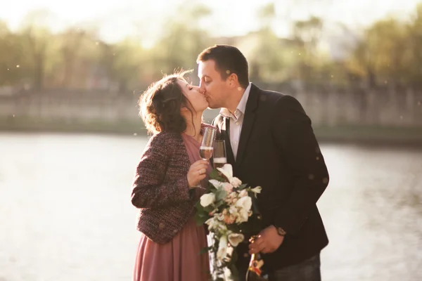 Çift düğün, damat ve bir cam Nehri yakınında günbatımında poz elbise — Stok fotoğraf