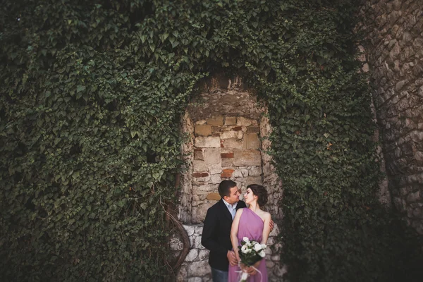 Pareja de boda de lujo abrazos y besos en el fondo hermosas plantas, cueva cerca del antiguo castillo —  Fotos de Stock