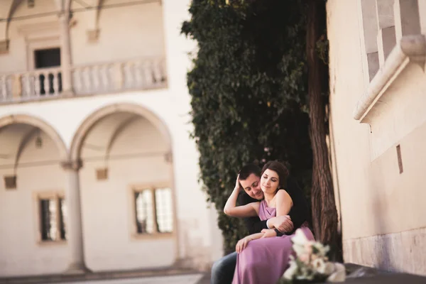 Szczęśliwy, ślub, para, pan młody, panna młoda z różowej sukience przytulanie i uśmiechając się nawzajem na tle ściany w zamku — Zdjęcie stockowe