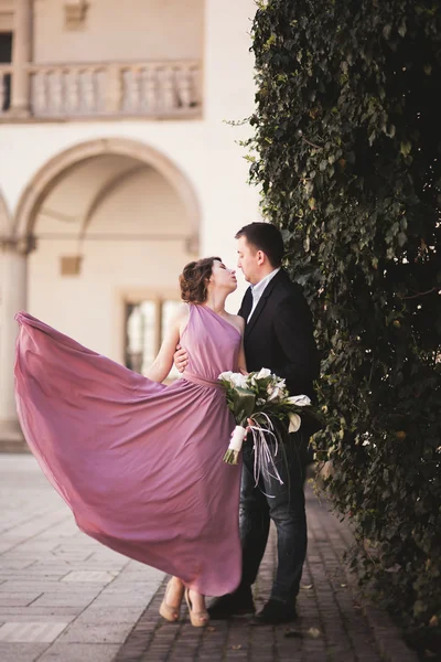 Prachtige paar, man, meisje met lange roze jurk poseren in oud kasteel in de buurt van kolommen. Krakau Vavel — Stockfoto