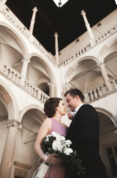 Happy wedding couple, groom, bride with pink dress hugging and smiling each other on the background walls in castle — Stock Photo, Image