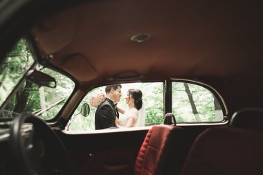 Şık düğün çift, Gelin, damat öpüşme ve retro arabanın yakınında sonbaharda sarılma