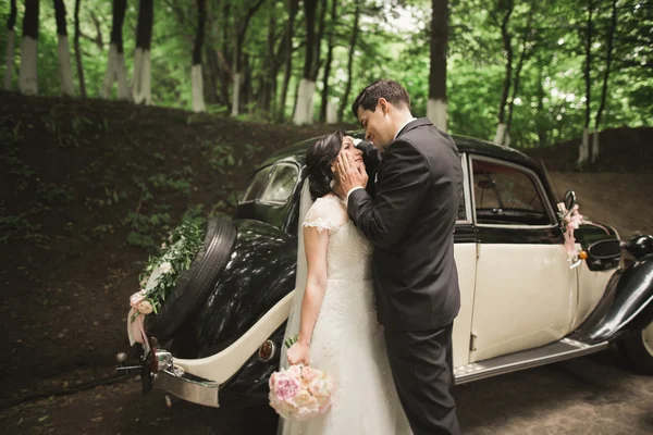 Стильна весільна пара, наречена, наречений цілується і обіймається біля ретро-автомобіля восени — стокове фото