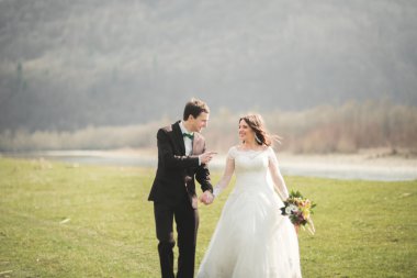 Güzel düğün çift, Gelin, poz ve yüksek Dağları arka planı alanında yürüme damat