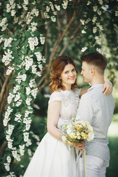 Glückliches Hochzeitspaar beim Spaziergang in einem botanischen Park — Stockfoto