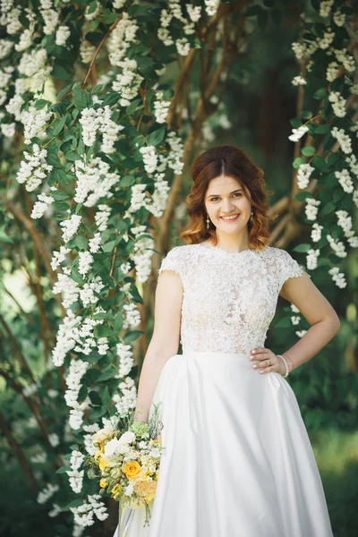 Hermosa novia joven de lujo en vestido de novia posando en el parque — Foto de Stock