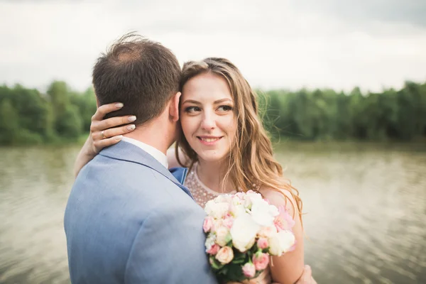 Νύφης και του γαμπρού κρατώντας όμορφη γαμήλια ανθοδέσμη. Λίμνη, δάσος — Φωτογραφία Αρχείου