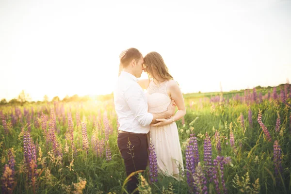 Vackra bröllopsparet, kärlek på solnedgången. Fielf med blommor — Stockfoto