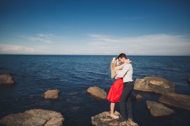 Deniz, mavi gökyüzü yakınındaki taş poz romantik sevgi dolu Çift